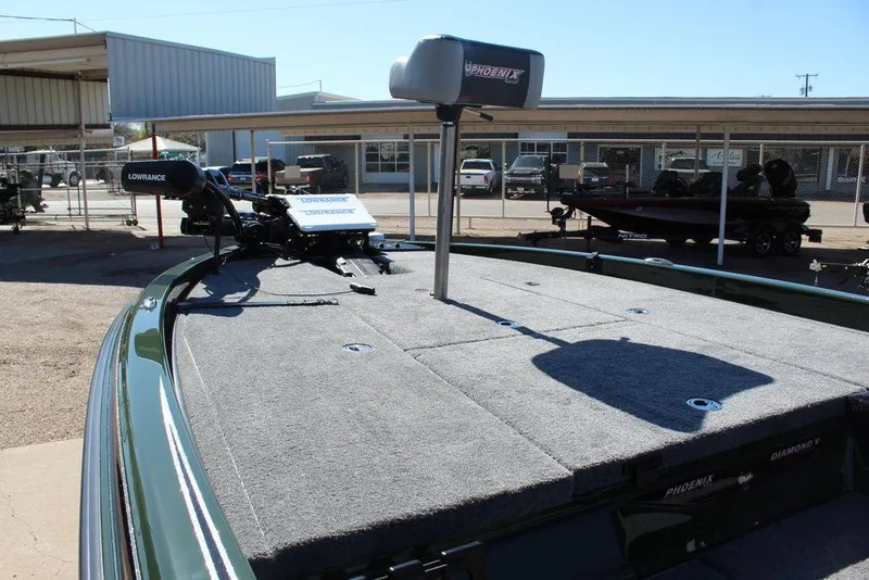 Slide: The Image of 2025 Phoenix 920 Elite II boat deck with fishing equipment, parked in a marina. - 17