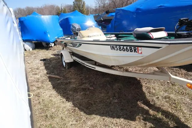 Slide: The Image of 1999 Lowe 170 boat on trailer, parked outdoors with blue covers in background. - 10