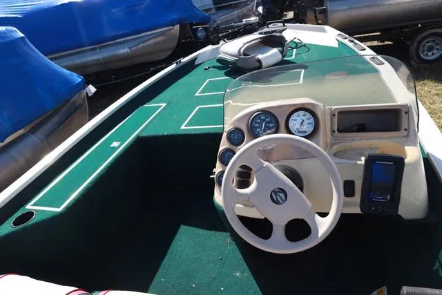 Slide: The Image of 1999 Lowe 170 boat interior with steering wheel and dashboard, featuring green carpet. - 3
