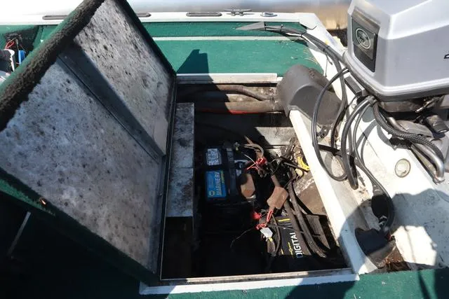 Slide: The Image of 1999 Lowe 170 boat battery compartment with open hatch and visible wiring. - 5