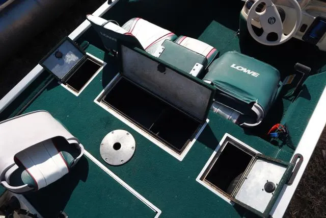 Slide: The Image of 1999 Lowe 170 boat interior with green carpet, storage compartments, and seating. - 6