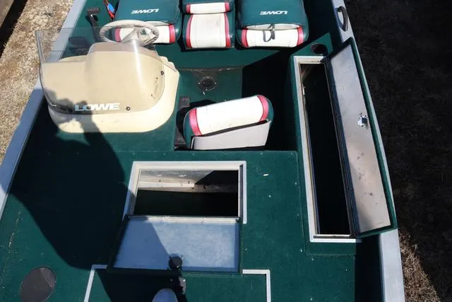 Slide: The Image of 1999 Lowe 170 boat interior with green carpet, open storage compartments, and seating. - 8