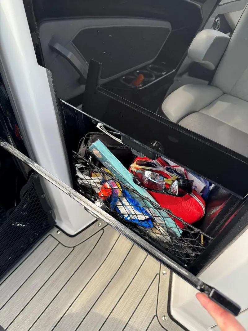 Slide: The Image of Storage compartment in a 2021 Yamaha Boats 252SE, containing various boating essentials. - 28