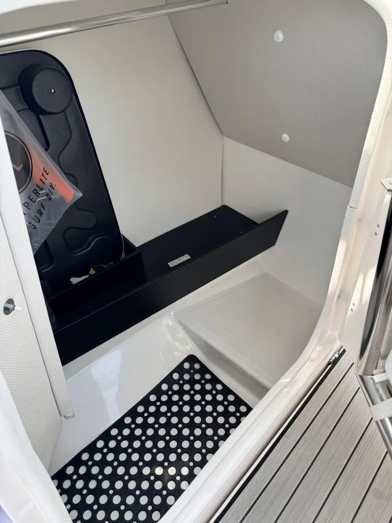 Slide: The Image of 2021 Yamaha Boats 252SE interior storage compartment with black shelving and polka dot mat. - 46