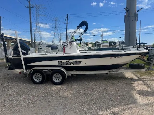 Slide: The Image of 2010 NauticStar 2110 Nautic Bay boat on trailer, parked outdoors under clear sky. - 1