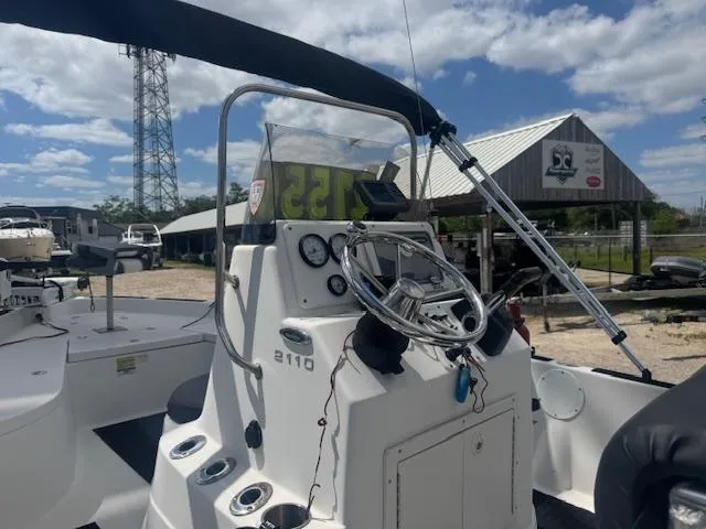 Slide: The Image of 2010 NauticStar 2110 Nautic Bay boat console with steering wheel and gauges, under a clear sky. - 16