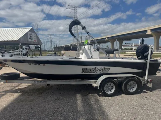 Slide: The Image of 2010 NauticStar 2110 Nautic Bay boat on trailer, parked outdoors under cloudy sky. - 2