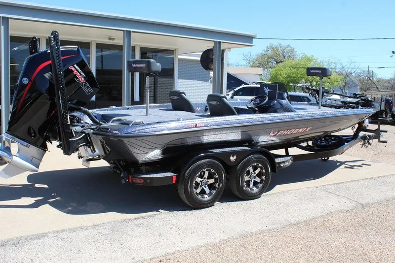 Slide: The Image of 2025 Phoenix 921 ELITE bass boat with dual axle trailer, parked outdoors. - 2