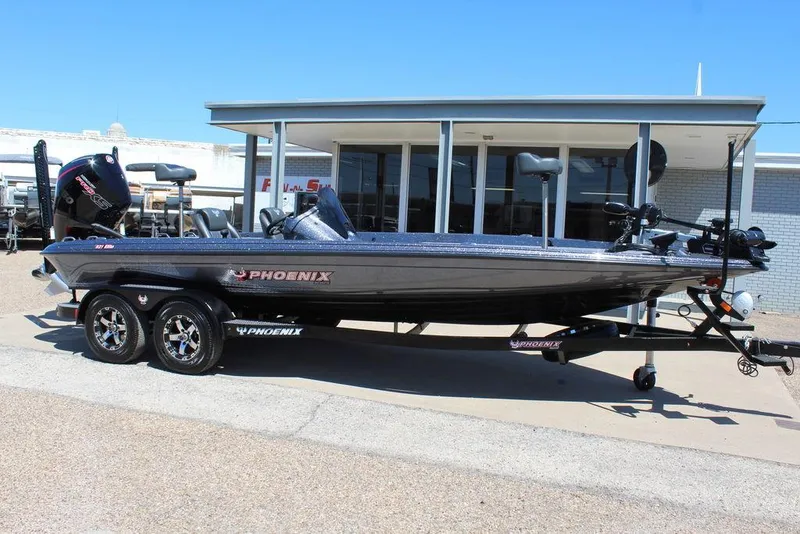 Slide: The Image of 2025 Phoenix 921 ELITE boat on trailer, parked outside a building under clear blue sky. - 26
