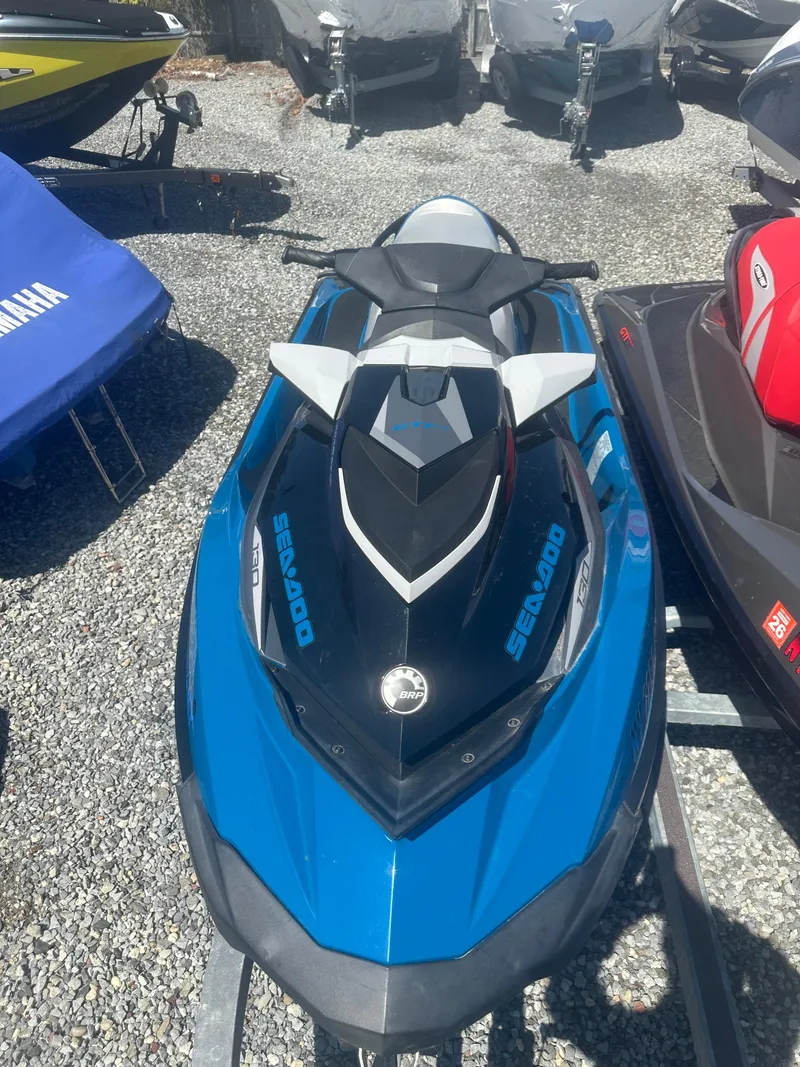 Slide: The Image of 2019 Sea-Doo GTI SE 130 jet ski in blue, parked on gravel. - 2