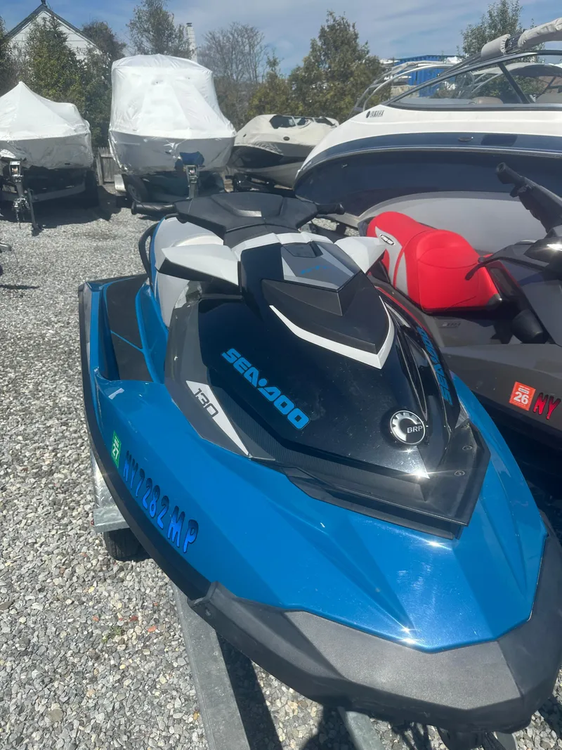 Slide: The Image of 2019 Sea-Doo GTI SE 130 jet ski in blue, parked on gravel with other boats. - 9