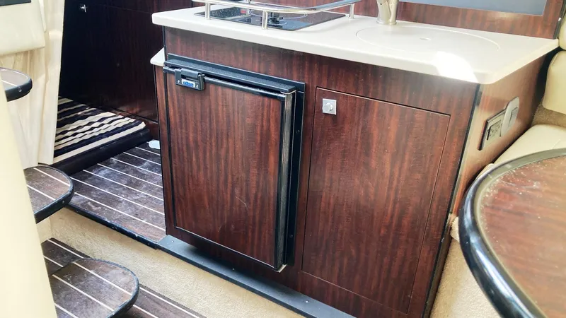 Slide: The Image of 2018 Monterey 275 Sport Yacht interior with wood cabinetry and compact kitchen area. - 14