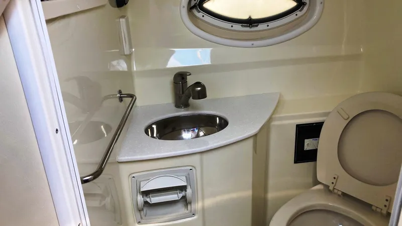 Slide: The Image of 2018 Monterey 275 Sport Yacht bathroom with sink, toilet, and porthole window. - 17
