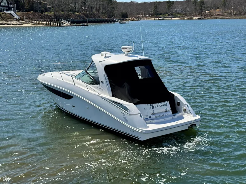Slide: The Image of 2014 Sea Ray 370 Sundancer cruising on a serene lake with wooded shoreline. - 11