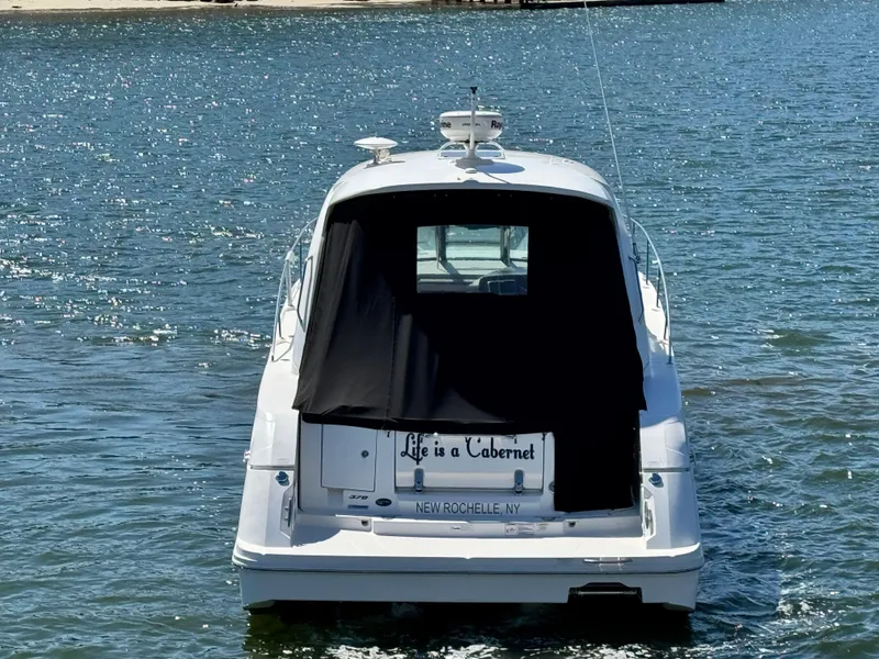 Slide: The Image of 2014 Sea Ray 370 Sundancer boat on water, rear view with black cover. - 13