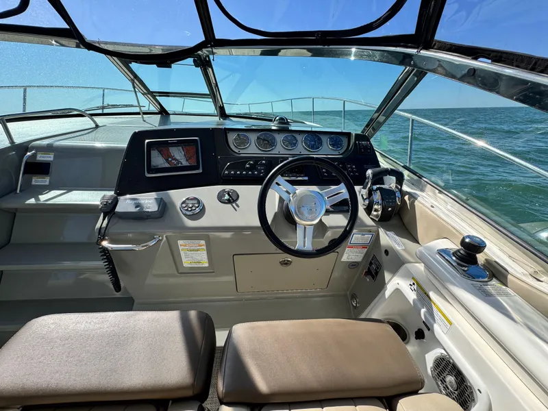 Slide: The Image of 2014 Sea Ray 370 Sundancer helm with steering wheel and navigation controls. - 26