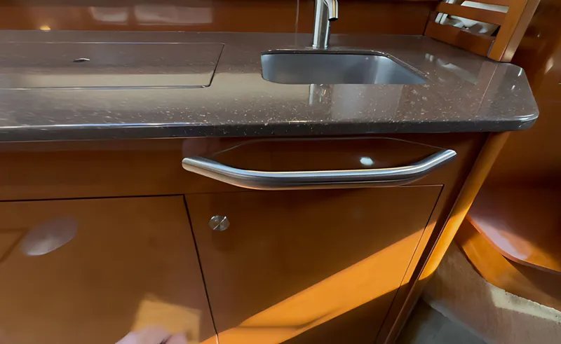 Slide: The Image of 2014 Sea Ray 370 Sundancer kitchen area with sink and wooden cabinetry. - 46