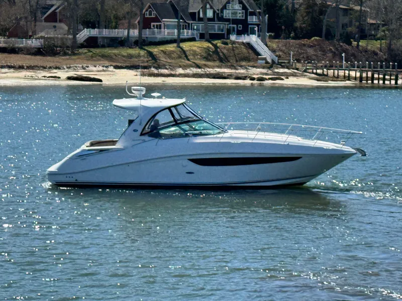 Slide: The Image of 2014 Sea Ray 370 Sundancer yacht cruising on a sunny day near a shoreline. - 5