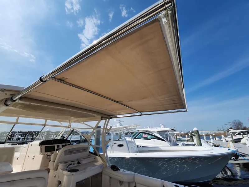 Slide: The Image of 2016 Grady-White Freedom 335 boat with extended canopy, docked under clear blue sky. - 17