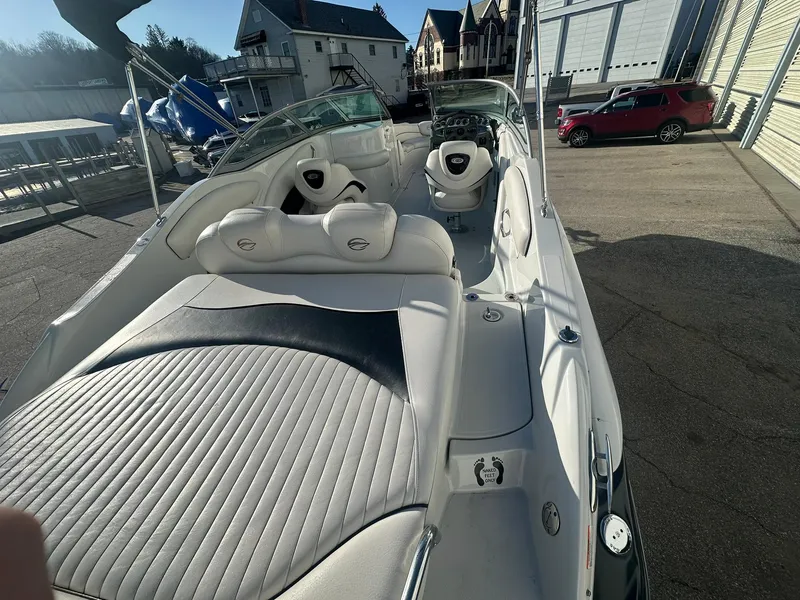 Slide: The Image of 2007 Crownline 260 LS boat interior with white seating and dashboard, parked outdoors. - 10