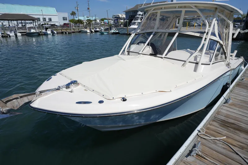 Slide: The Image of 2022 Grady-White Freedom 235 boat docked in a marina, clear sky background. - 12