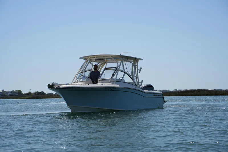 Slide: The Image of 2022 Grady-White Freedom 235 boat cruising on calm waters under clear sky. - 2