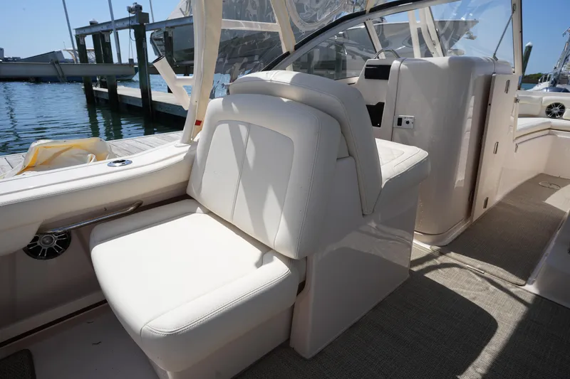 Slide: The Image of 2022 Grady-White Freedom 235 boat interior with white seating and helm, docked by the water. - 20