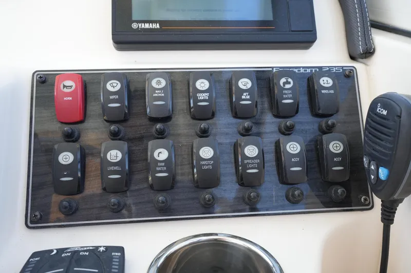 Slide: The Image of Control panel of 2022 Grady-White Freedom 235 boat with various switches and a microphone. - 28
