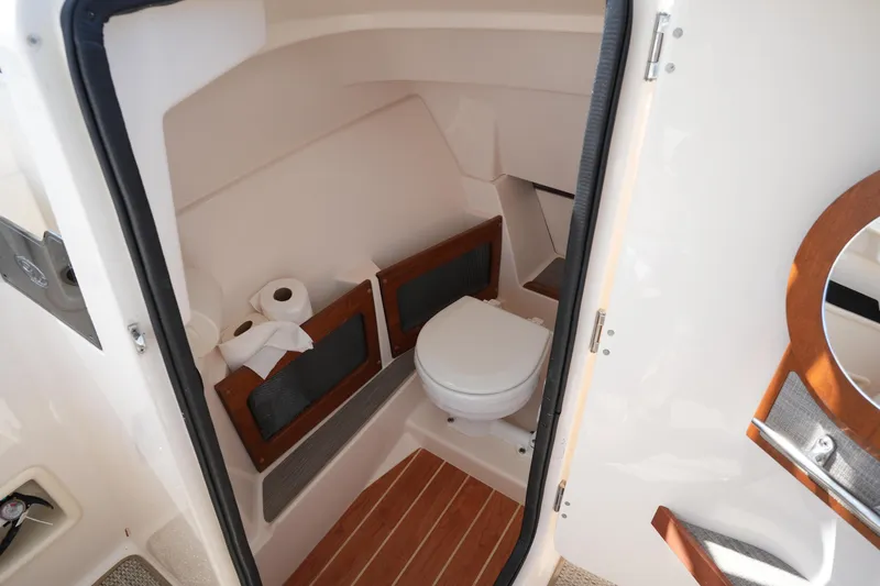 Slide: The Image of 2022 Grady-White Freedom 235 boat interior with compact bathroom and wooden flooring. - 31