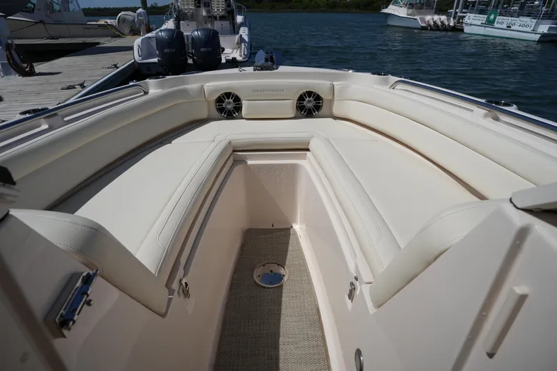 Slide: The Image of 2022 Grady-White Freedom 235 boat interior with cushioned seating and speakers, docked by the water. - 32