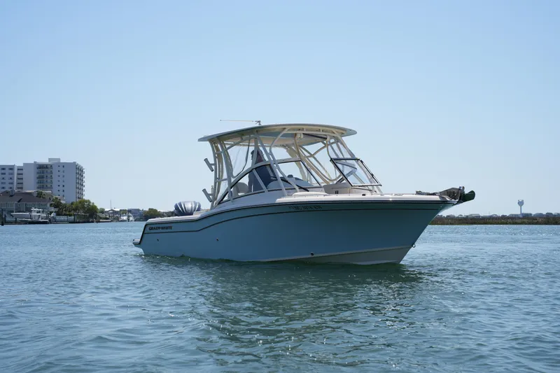 Slide: The Image of 2022 Grady-White Freedom 235 boat on calm water, with buildings in the background. - 5