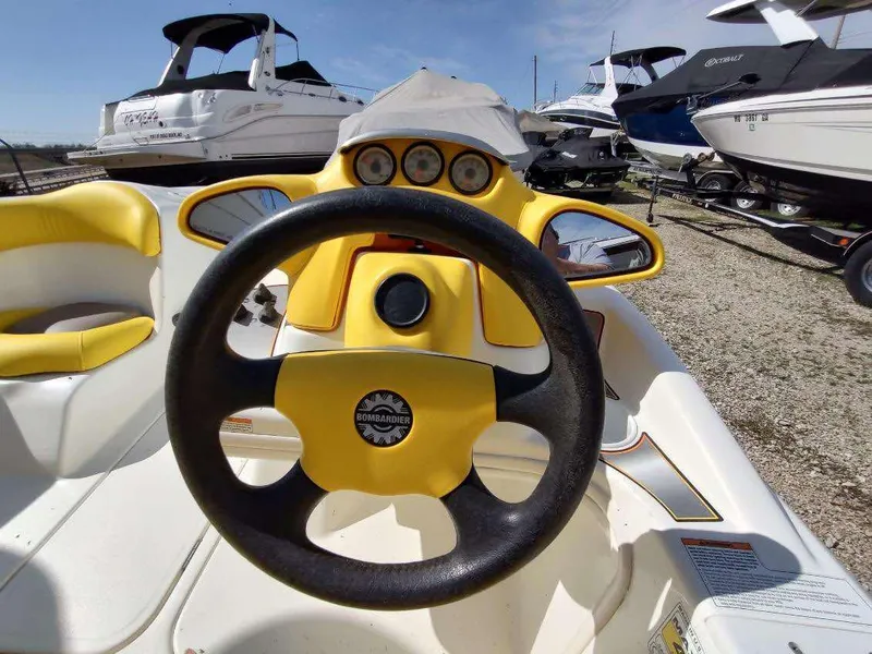 Slide: The Image of 2004 Sea-Doo Sportster boat dashboard with steering wheel, surrounded by other boats. - 2