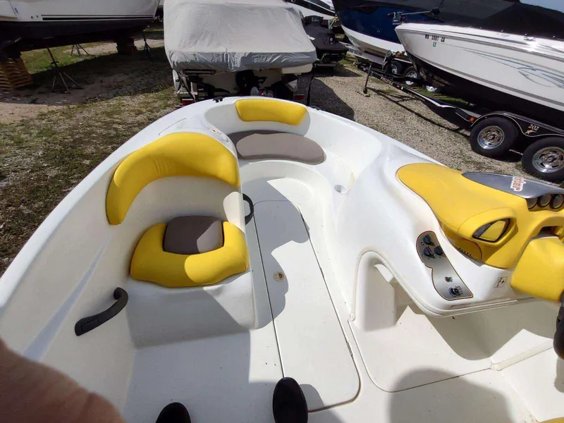 Slide: The Image of 2004 Sea-Doo Sportster boat interior with yellow and gray seating, parked among other boats. - 9