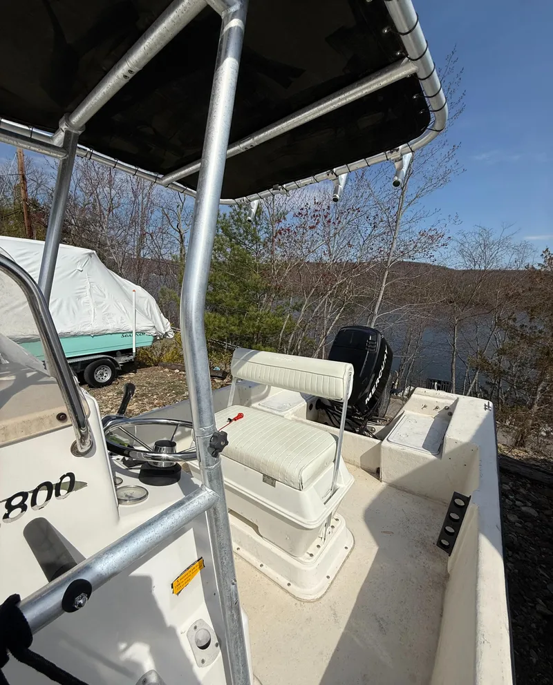 Slide: The Image of 2010 May-Craft 1800 Skiff boat with seating, steering wheel, and outboard motor, near a lake. - 8