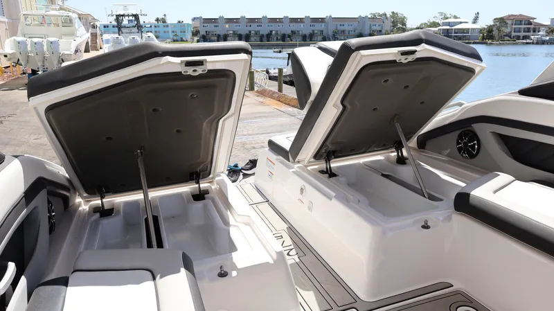 Slide: The Image of 2020 Yamaha Boats 275 SD open storage compartments by the water. - 13