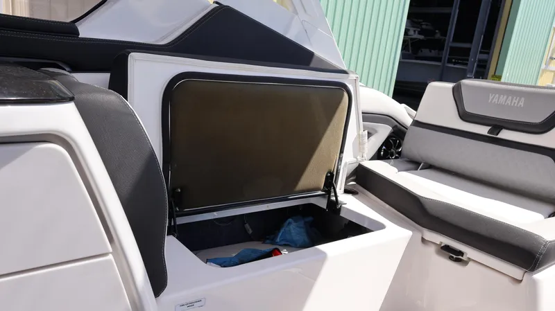 Slide: The Image of 2020 Yamaha Boats 275 SD interior storage compartment with open hatch, showcasing seating and storage space. - 20