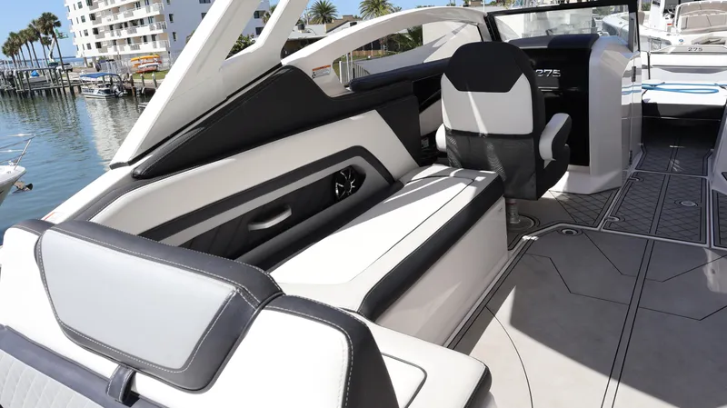 Slide: The Image of 2020 Yamaha Boats 275 SD interior with sleek seating and modern design in a marina setting. - 23