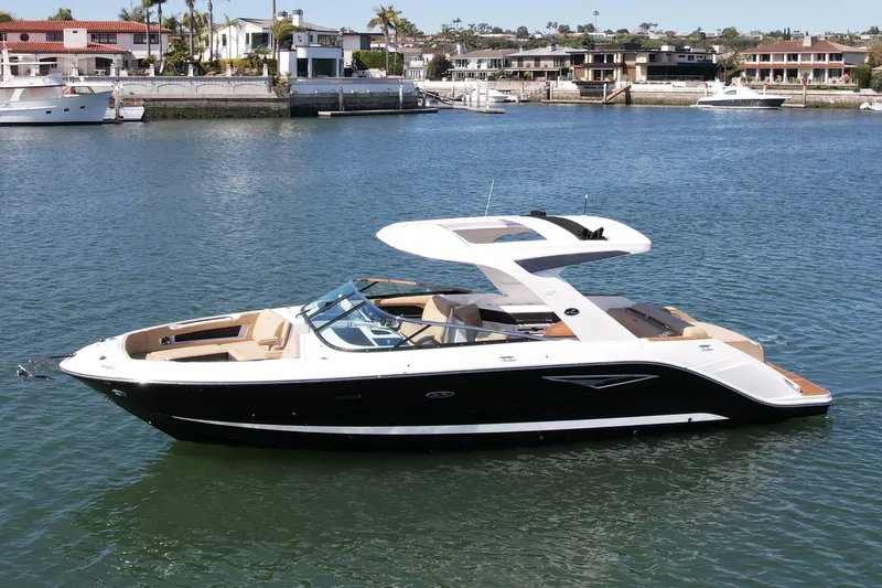 Slide: The Image of 2019 Sea Ray SLX 310 boat on calm water near waterfront homes. - 0
