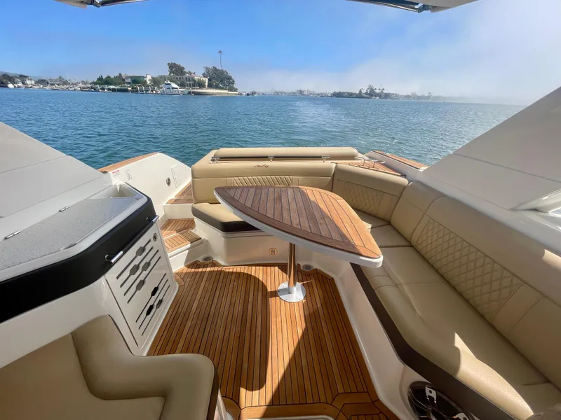 Slide: The Image of Luxurious 2019 Sea Ray SLX 310 boat interior with elegant seating and wooden table on a sunny day. - 16
