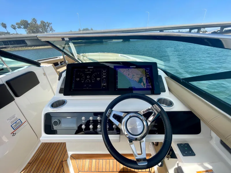 Slide: The Image of 2019 Sea Ray SLX 310 helm with modern navigation display and steering wheel on open water. - 35