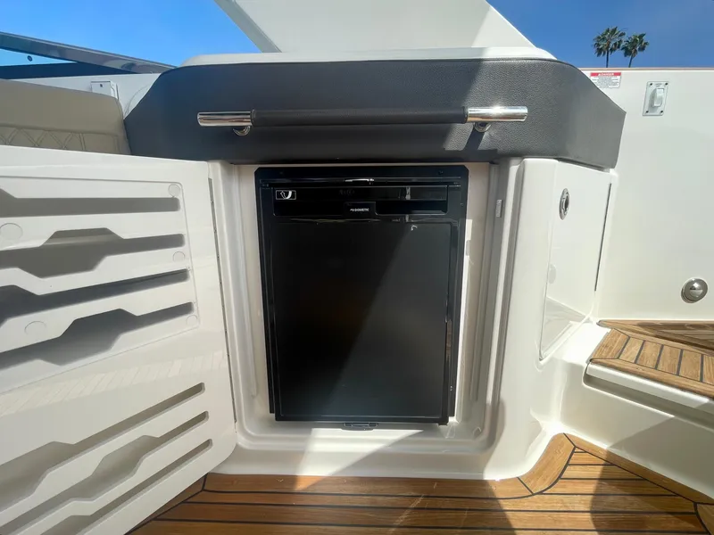 Slide: The Image of 2019 Sea Ray SLX 310 boat interior with built-in mini fridge and wooden flooring. - 42