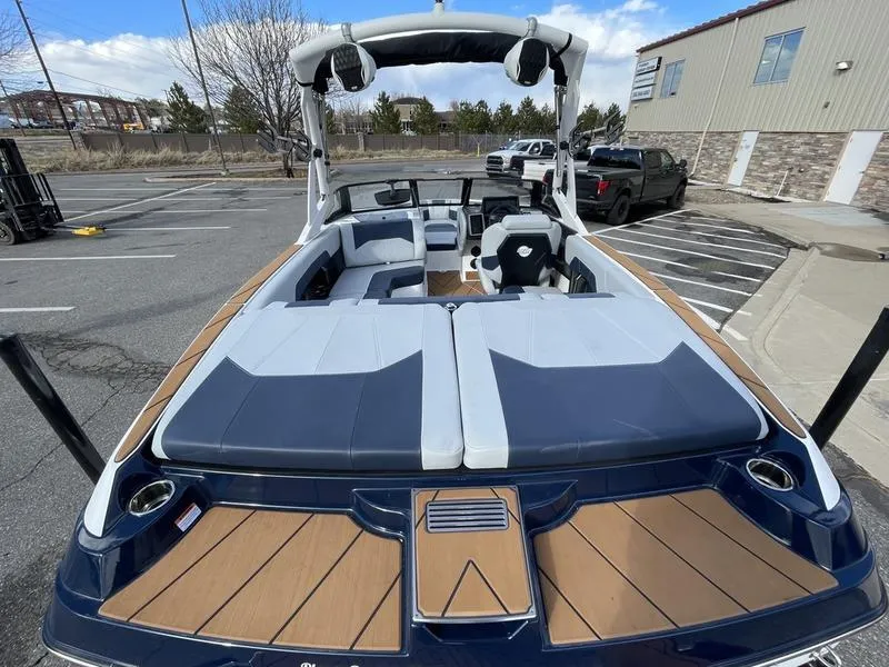 Slide: The Image of 2025 Malibu 20 VTX boat with sleek design and spacious seating in a parking lot. - 10