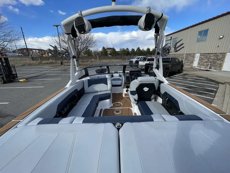 Slide: The Image of 2025 Malibu 20 VTX boat interior with spacious seating and modern design in a parking lot. - 11