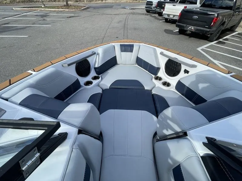 Slide: The Image of 2025 Malibu 20 VTX boat interior with sleek seating and cup holders in a parking lot. - 17