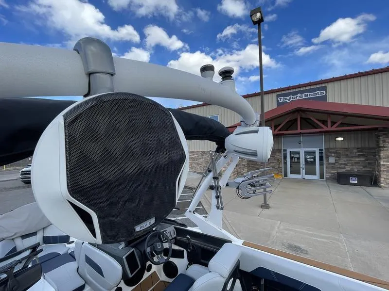 Slide: The Image of 2025 Malibu 20 VTX boat with speaker, parked outside Taylor's Boats under a blue sky. - 22