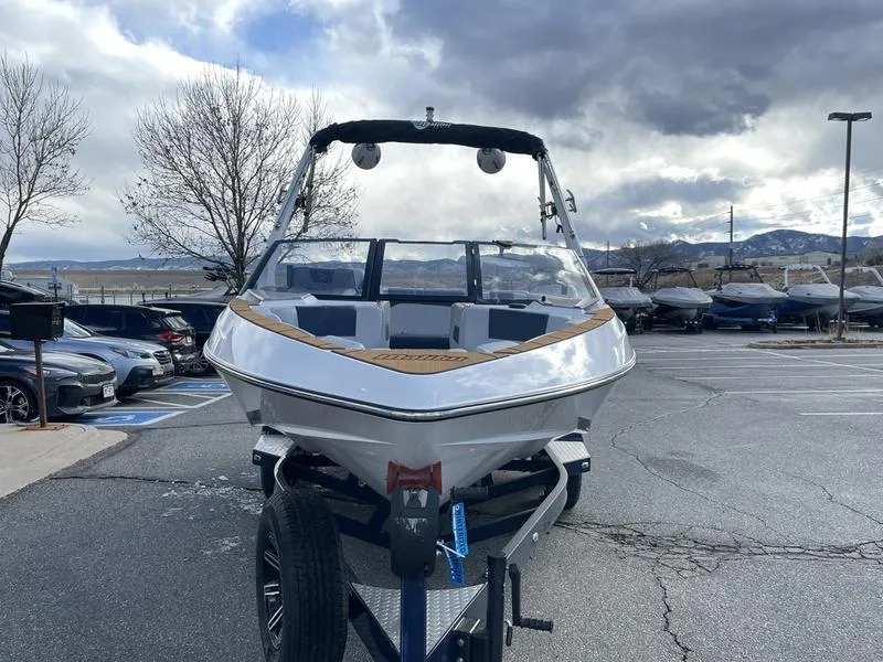 Slide: The Image of 2025 Malibu 20 VTX boat on trailer in parking lot, cloudy sky background. - 4