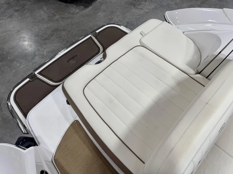 Slide: The Image of 2012 Cobalt 262 BR boat interior with white cushioned seating and brown accents. - 10