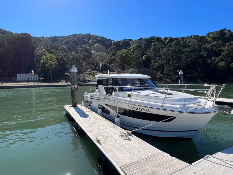 Slide: The Image of 2019 Jeanneau NC Weekender 1095 docked on a sunny day, surrounded by lush greenery. - 0