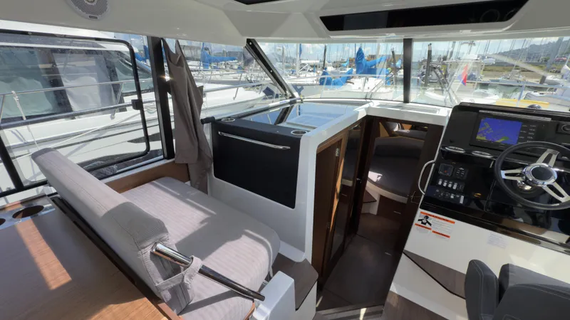 Slide: The Image of 2019 Jeanneau NC Weekender 1095 interior with helm, seating, and marina view. - 22