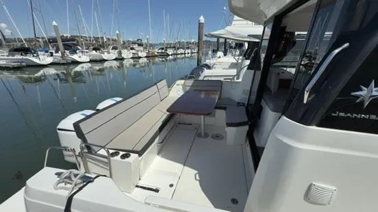 Slide: The Image of 2019 Jeanneau NC Weekender 1095 docked, featuring spacious deck seating and table. - 6